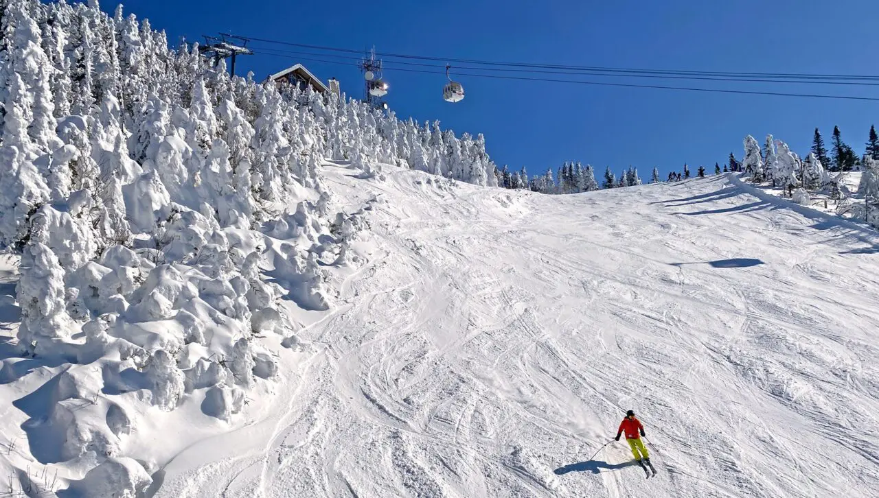 Skier on Mont Tremblant slopes with aerial gondolas on the background