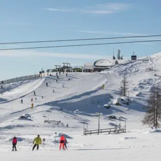 Ski slopes, skiers and cable cars on a sunny day in the Dolomites, Brenta area. Madonna di Campiglio, the top of the Pradalago cable car. Italy